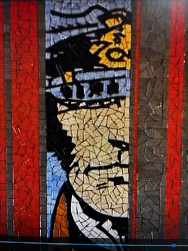 Mosaïque représentant un personnage en partie visible, avec des couleurs vives et un fond texturé.