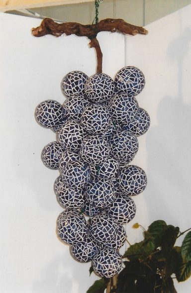 Grappes de raisin décoratives en céramique suspendues à une branche.